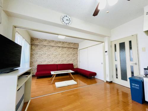 a living room with a red couch and a table at 札幌中心 ｻｰﾋﾞｽｱﾊﾟｰﾄﾒﾝﾄSapporo中島公園2LDK 901 in Sapporo