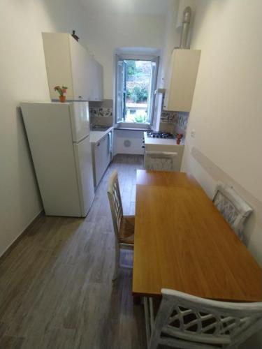 eine Küche mit einem Holztisch mit Stühlen und einem Kühlschrank in der Unterkunft Appartamento Viola in Pietra Ligure