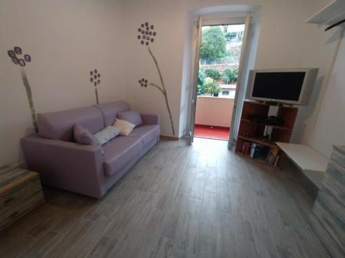 ein Wohnzimmer mit einem lila Sofa und einem TV in der Unterkunft Appartamento Viola in Pietra Ligure