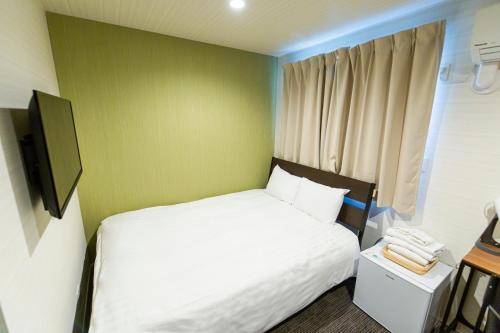 ein Schlafzimmer mit einem weißen Bett und einer grünen Wand in der Unterkunft GLOU Higashi Shinjuku in Tokio