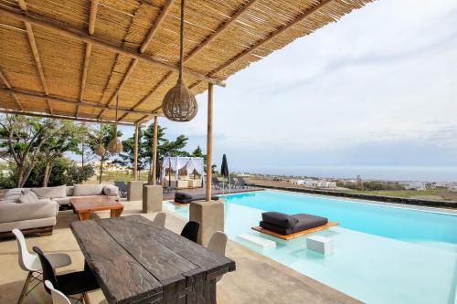 an outdoor dining area with a table and a swimming pool at A&V Sea View Villa in Fira