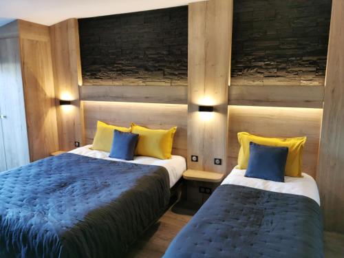 a bedroom with two beds with blue and yellow pillows at Maison de Laveline in Laveline