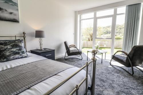 - une chambre avec un lit, deux chaises et une fenêtre dans l'établissement 2 Pensyflog Barns, à Porthmadog