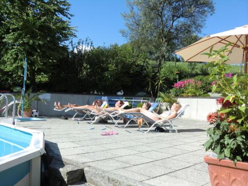 eine Gruppe von Menschen, die in Gartenstühlen in der Nähe eines Schwimmbads liegen in der Unterkunft Ferienpension Fremuth in Ruhmannsfelden