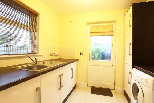 a kitchen with a sink and a washing machine at Ardmullen Walnut 3 Bed Holiday Home in Kenmare