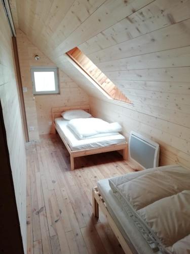 une chambre mansardée avec deux lits et une lucarne dans l'établissement Gîte Granit des Fraux, à Besse-et-Saint-Anastaise