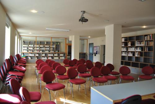 Ono San Pietro的住宿－Ostello Centro Concarena，图书馆里的一个红色椅子的房间