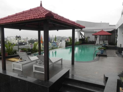 a swimming pool with chairs and a gazebo at Regenta Central RS Chennai OMR SIPCOT in Chennai