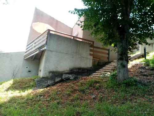 a building with stairs and a tree next to it at Appartement terrasse +parking in Vieille-Brioude