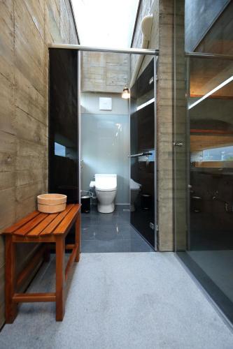 a bathroom with a toilet and a wooden bench at Penlai Home in Fengli