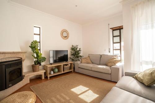 a living room with a couch and a tv at Ericeira Paradise House&Suites in Ericeira