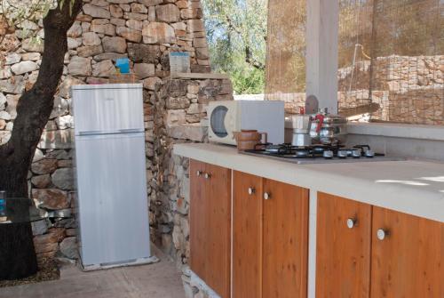 a kitchen with a white refrigerator and a stone wall at Piccolo Trullo Salentino in Marina di Pescoluse