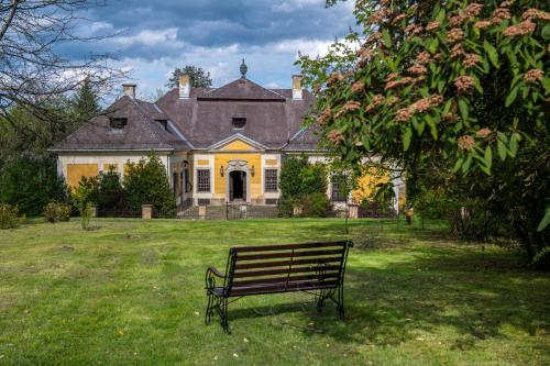 a park bench in front of a large house at Tündérkert Hotel Noszvaj in Noszvaj