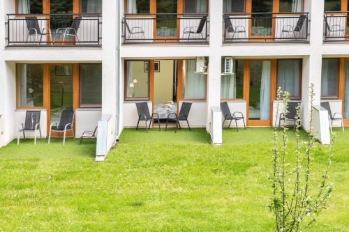 a house with chairs and a table on the lawn at Tündérkert Hotel Noszvaj in Noszvaj