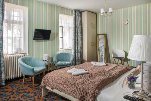 ノスヴァイにあるTündérkert Hotel Noszvajのベッドルーム1室(ベッド1台、椅子2脚、鏡付)
