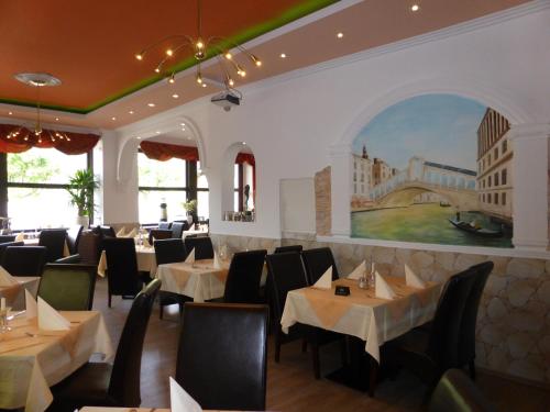 ein Restaurant mit Tischen und Stühlen und einem Gemälde an der Wand in der Unterkunft Rheinhotel Zur Krone in Boppard