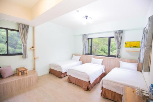 2 Betten in einem Zimmer mit Fenstern in der Unterkunft 亞窩行館 Yao Guesthouse in Insel Nangan