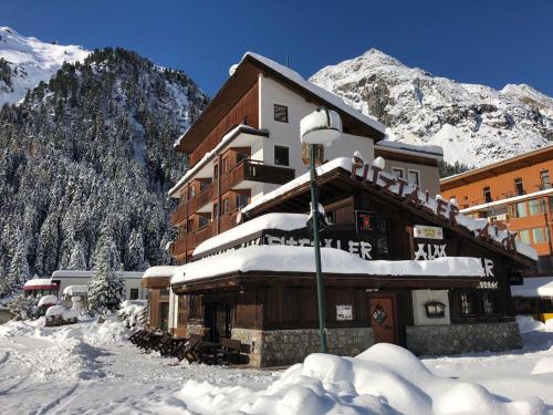 a building covered in snow in front of a mountain at Piz-Hotel in Sankt Leonhard im Pitztal