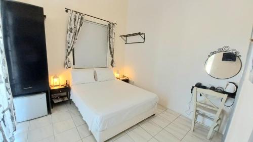 a small white bedroom with a bed and a mirror at Koukounari 2 Rooms in Skala