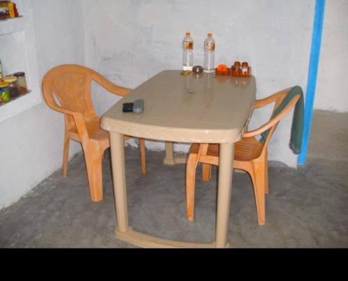 a wooden table with two chairs and two bottles on it at Vamoose Bablu in Khajurāho