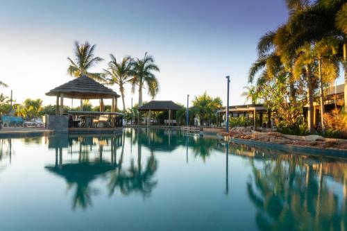 una piscina de agua con palmeras y un edificio en Ningaloo Caravan and Holiday Resort en Exmouth