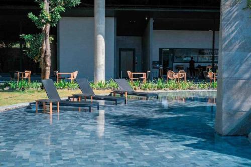 Livist Resort phetchabun في بيتشابون: مسبح وكراسي صالة وطاولة ومبنى