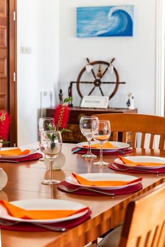 a wooden table with plates and wine glasses on it at Seafront Villa Ocean Pearl - Private Beach Area & Pool in Polis Chrysochous