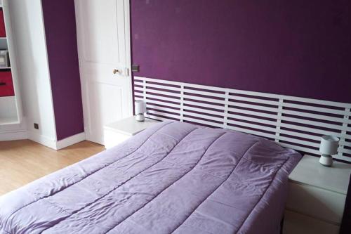 une chambre avec un lit avec un mur violet dans l'établissement Apt T2 41m2 WIFI 2* 4-6 pers. La BOURBOULE, à La Bourboule