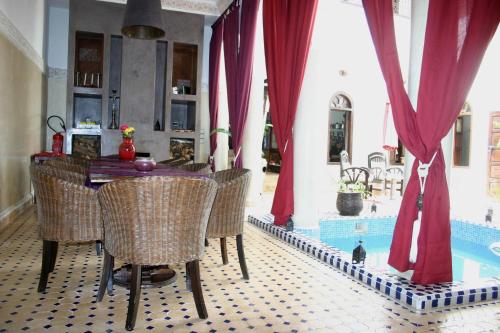 - une salle à manger avec une table et des chaises à côté de la piscine dans l'établissement Riad Elias & Spa, à Marrakech