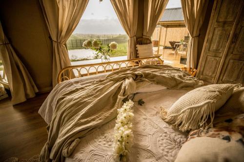a bedroom with a bed with a large window at Orchard Valley Glamping in Otorohanga