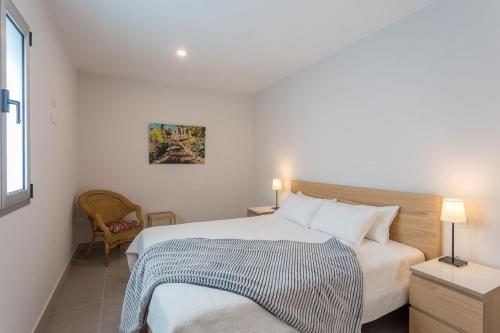 - une chambre blanche avec un lit et une chaise dans l'établissement Las Canteras Beach way apartment, à Las Palmas de Gran Canaria