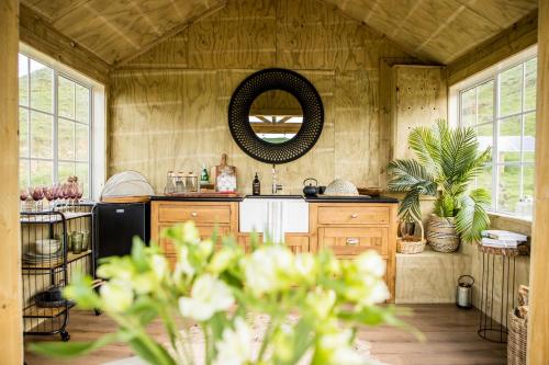 a kitchen with a sink and a mirror on the wall at Orchard Valley Glamping in Otorohanga