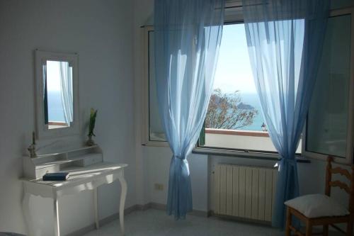 a bathroom with a sink and a window with blue curtains at Sea&sky in Praiano