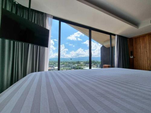 a bedroom with a large bed with a large window at Livist Resort phetchabun in Phetchabun