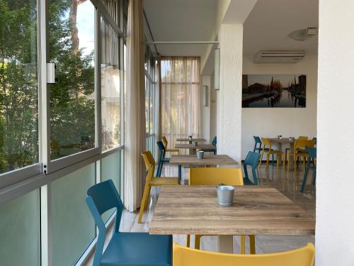 un restaurante con mesas y sillas de madera y ventanas en Hotel Chery en Milano Marittima