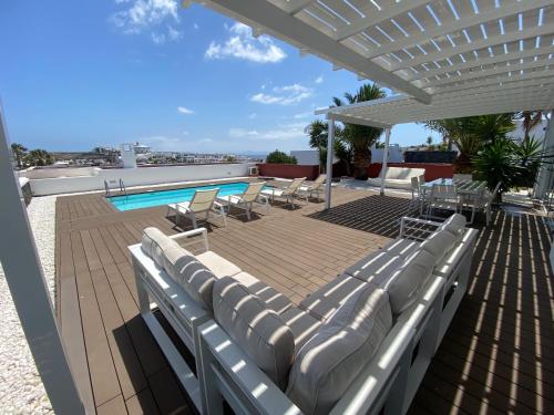 een patio met ligstoelen en een zwembad bij Villa Maria by Villalia in Playa Blanca