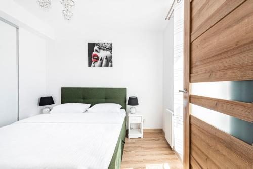 a bedroom with a bed with a green headboard at Apartament Zielony OPTILOCUS in Gdańsk