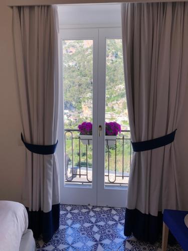 a bedroom with curtains and a door with a balcony at Villa Fortuna in Positano
