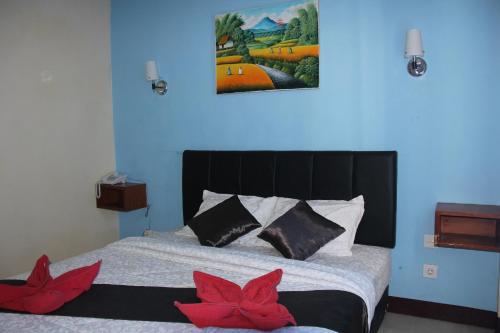 a bedroom with a bed with two red flowers on it at Asher Bali Transit in Kuta