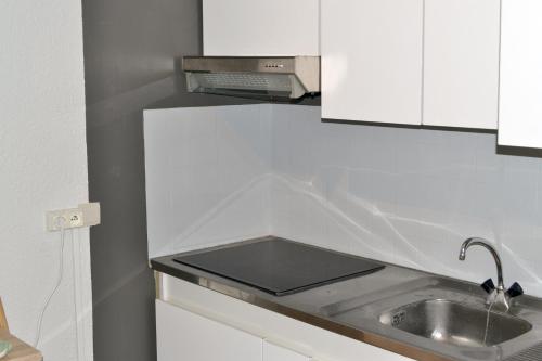 een keuken met een wastafel en witte kasten bij Studio classé 3 étoiles de 39m² au pied des thermes in Amélie-les-Bains-Palalda