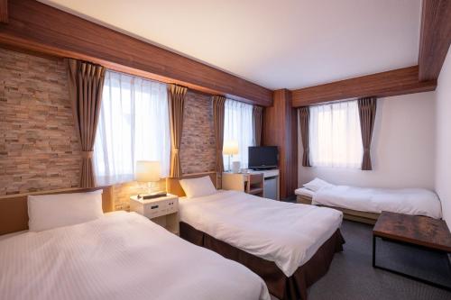 a hotel room with two beds and a tv at Business Inn Norte in Sapporo
