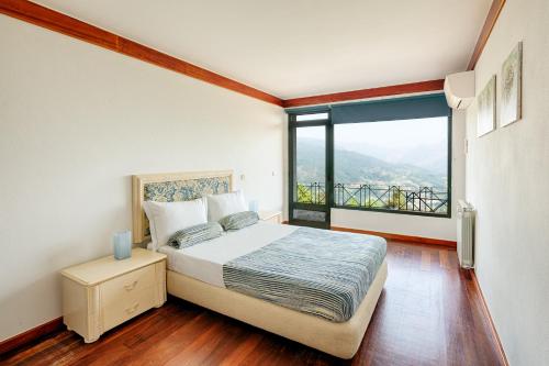 a bedroom with a bed and a large window at Casa Martagão do Gerês by Gerês Casas in Caniçada