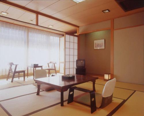 sala de estar con mesa de madera y sillas en Kamogawakan en Kyoto