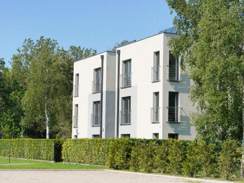 Biały budynek z żywopłotem przed nim w obiekcie Apartamenty Szmaragdowa 10 w mieście Mielno