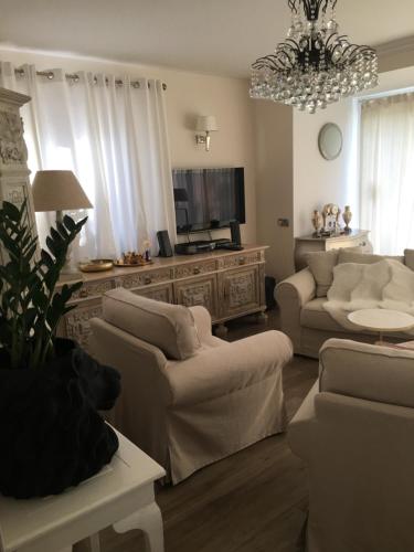 a living room with white furniture and a chandelier at Mazurska Villa Deluxe w Pasymiu z prywatnym pomostem na jezioro Kalwa i łodzią na wyłączność Najwyższe Premium w Osada Zamkowa in Pasym
