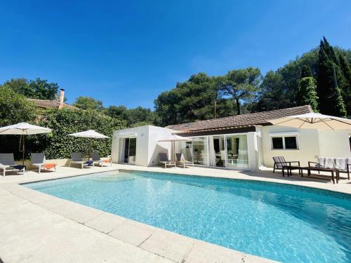 - une piscine avec des chaises et des parasols à côté d'une maison dans l'établissement Villa FG, à Mougins