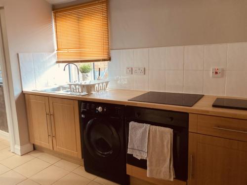 a kitchen with a washer and a sink and a washing machine at Stunning Stylish & Spacious Ground Floor Apartment, Kidderminster in Kidderminster