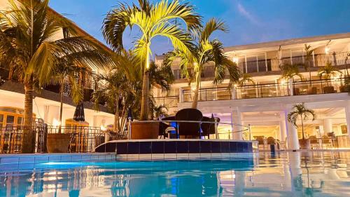 a swimming pool with palm trees in front of a building at Clarkton Hotel Apartment in Angeles