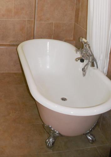 a white bath tub sitting in a bathroom at The Coach House in Hawkhurst