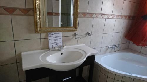a bathroom with a white sink and a tub at Country Blue Luxury Guest House in Polokwane